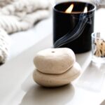 Elegant spa arrangement with stacked stones, a lit candle, and gentle smoke for relaxation.