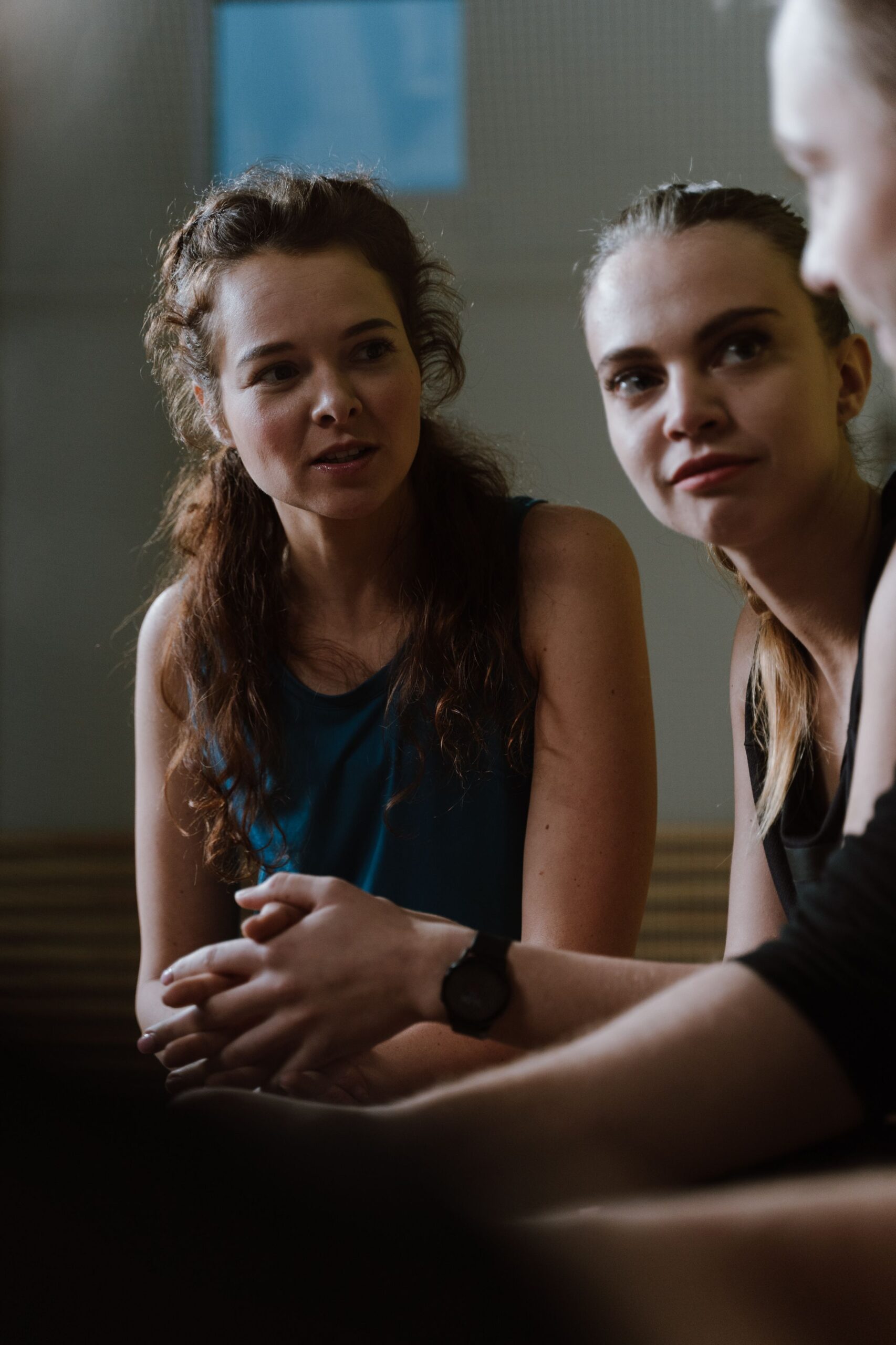Two women engaged in a relaxed conversation indoors, creating a warm social atmosphere.